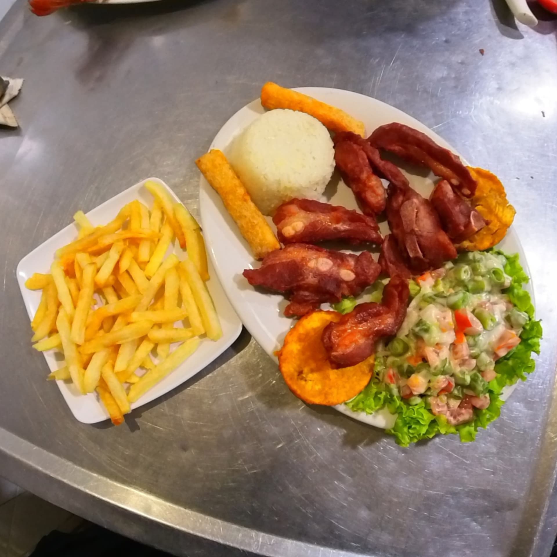 Plato con tocineta, arroz, patacón, yuca, ensalada y papas fritas