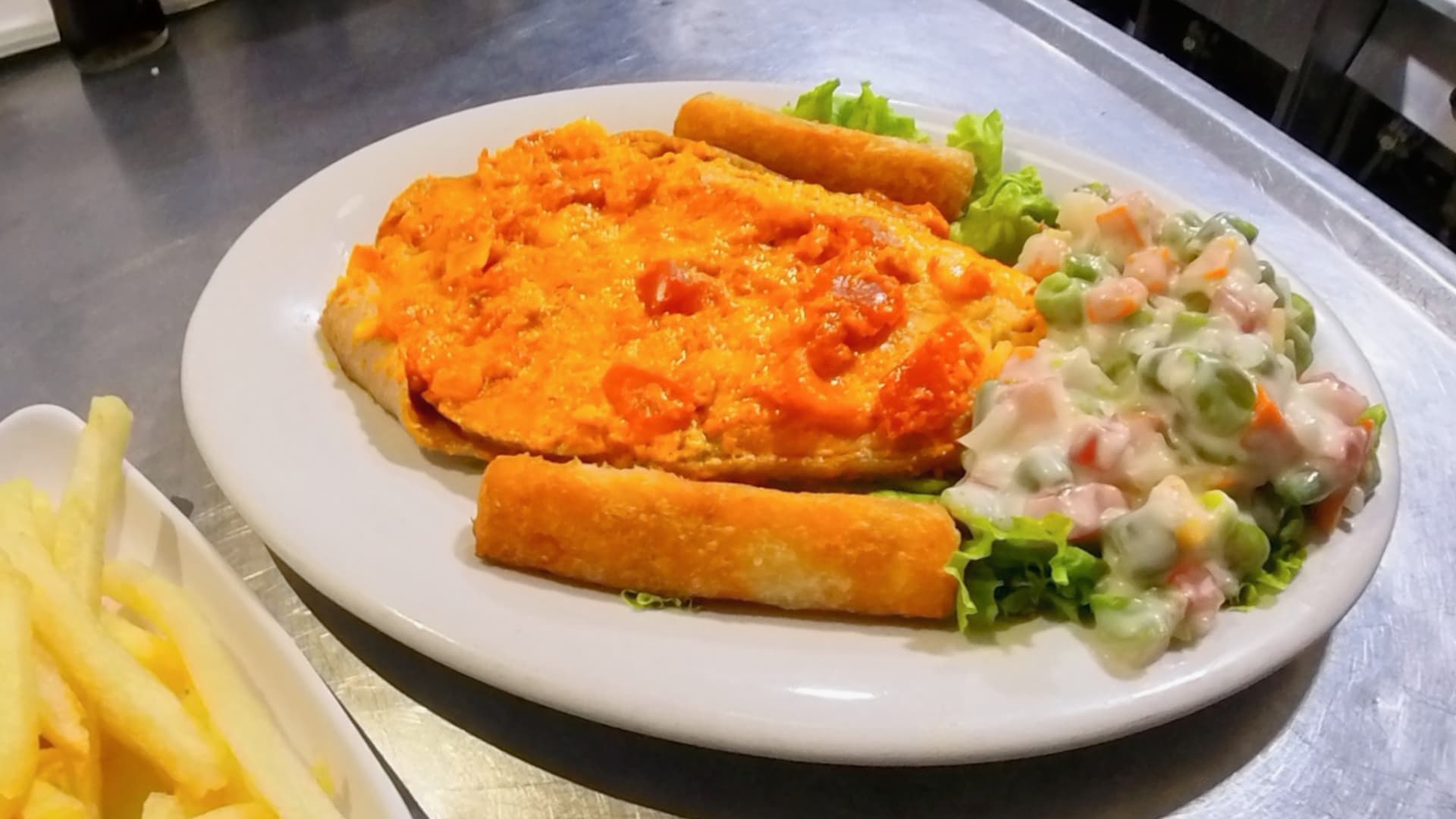 Filete de pescado gratinado con salsa, yuca y ensalada de verduras